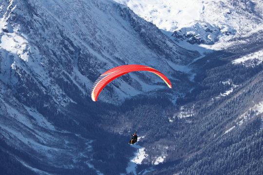 paraplane flying over snowy Caucasus mountains sunny blue sky