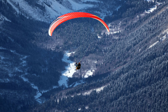 paraplane flying over snowy Caucasus mountains sunny blue sky