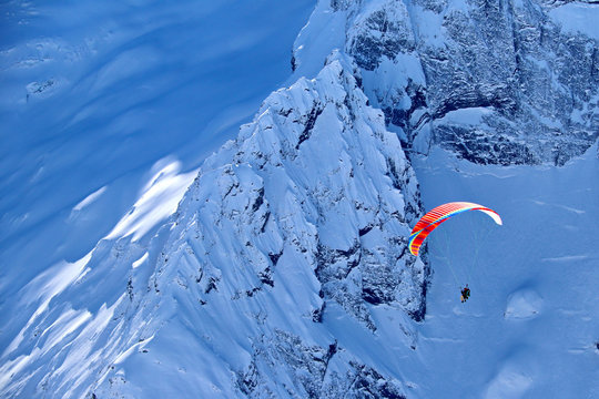 paraplane flying over snowy Caucasus mountains sunny blue sky