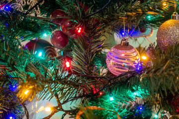 Obraz na płótnie Canvas Colourful fairy lights and baubles decorate a Christmas tree.