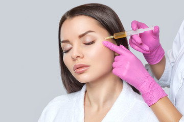 Fototapeta premium Cosmetologist does prp therapy on the face of a beautiful woman with clean skin in a beauty salon. There is in vitro blood plasma, ready for injection. Cosmetology concept.