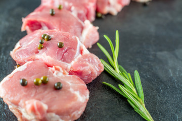 Raw pork tenderloin with green pepper on a dark gray background slate black slate blackboard. Close up
