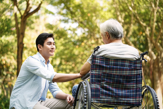 asian son comforting wheelchair bound father