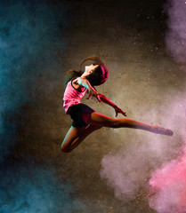 Street dance girl dancer jumping up dancing in neon light doing gymnastic exercises in studio on...