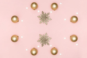 New Year and Christmas composition. Frame from golden balls, white stars, snowflake on pastel pink background. Top view, flat lay, copy space