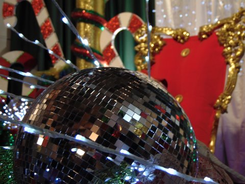 Christmas decoration on a background. A big silver Christmas ball and a working garland against the background of the throne of Santa Claus and Christmas decorations in blur..