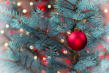Single Red Ornament hanging from pine tree with glowing lights  in vinatage format