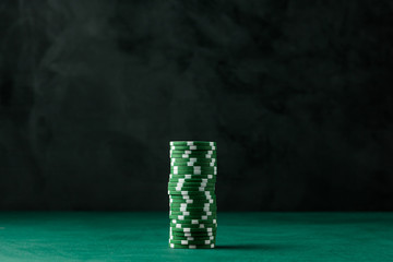 Stack of poker green chips on the table on a black background