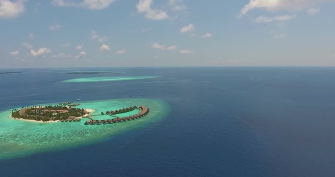 Maldivian resort aeral view taken by drone of tropical island with clear blue transparent turquoise ocean water. Blue cloudy sunny sky. Concept of sea coast  summer tropical vacation. 