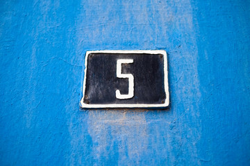 Elegant number 5, five, dark blue plate on light blue weathered background.