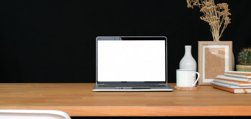 Cropped shot of trendy office room with mock-up laptop computer and copy space on wooden table with black wall