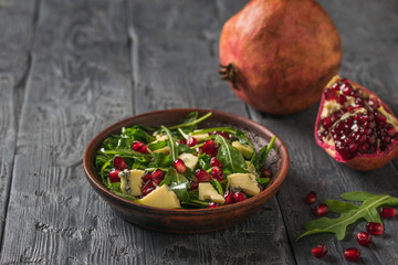 Salad of arugula, cheese and pomegranate on the background of fresh pomegranates.