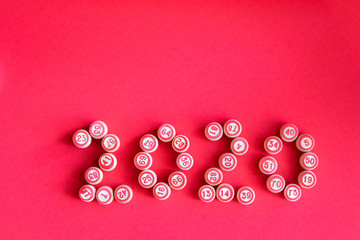 The inscription 2020 is laid out from bochenko for the game of Lotto on a bright red background. New year, copy space, top view.