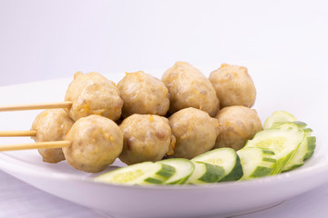 Grilled meatballs and cucumbers on a white plate