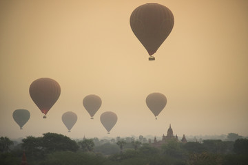 Sunrise with dusty smoke and many hot air balloons above The Bagan Archaeological Zone in Myanmar