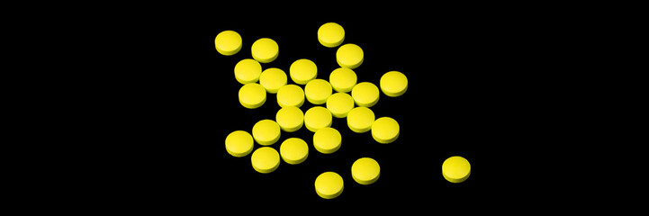 Yellow pills are scattered on a black background.
