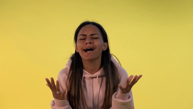 Desperate multiethnic woman spreading her hands to the sides on yellow background. She asking why