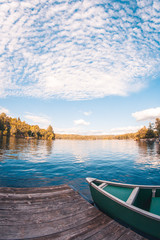 Reflections of a cloudy blue sky viewed from the dock of a lake house in Québec, Canada
