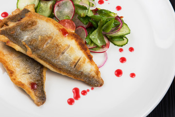 Fillet of zander with vegetables on a plate in a restaurant.