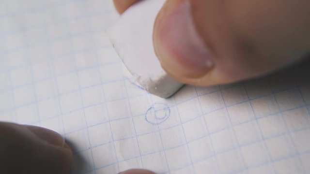 man fingers use white rubber eraser to remove face picture from checkered paper extreme close view