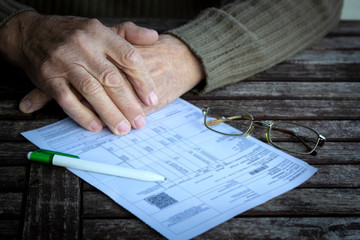 Hands of old senior man fills in utility bills on wooden table. Planning month budget, calculating...