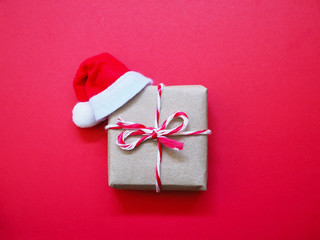 Close up handmade gift box and santa claus hat on red background.