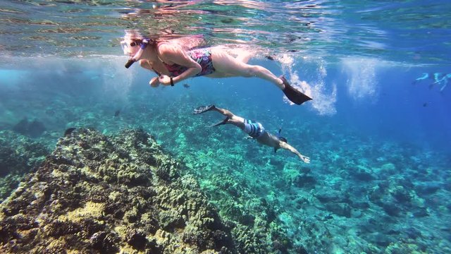 Man And Woman Swimming At Coral Reef In Tropical Blue Sea