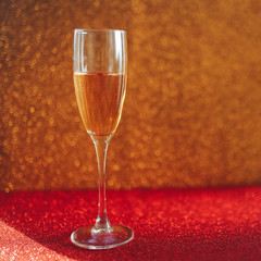 One glass champagne on gold blurred background near christmas balls, gold. Happy new year.