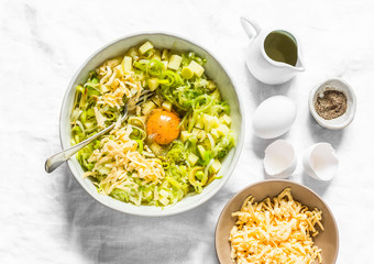 Ingredients for cooking leeks, zucchini, potato frittata on a light background, top view