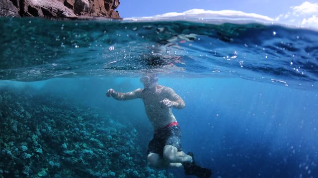 Man Swimming Beside Coral Reef In Tropical Blue Sea