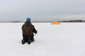Fototapeta na wymiar Man raises a kite on the snow, Ob reservoir, Novosibirsk, Russia