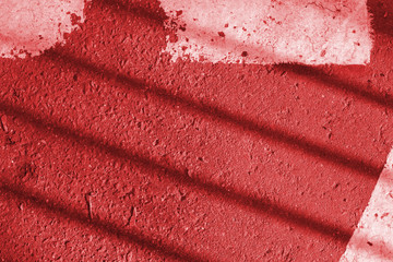 Asphalt surface with old white paint and fence shadow on it. Abstract background red color toned