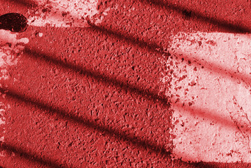 Asphalt surface with old white paint and fence shadow on it. Abstract background red color toned