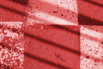 Asphalt surface with old white paint and fence shadow on it. Abstract background red color toned