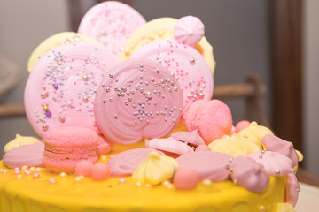 Candy bar. A big yellow pink cake with round gingerbread, marshmallows on the table.Beautiful tasty cake decorated with zephyr for big party.Fondant covered pastels coloured birthday cake.