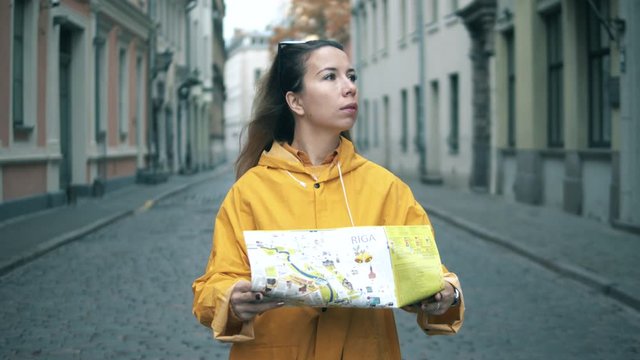 Young woman looks at a map of Riga on a street.