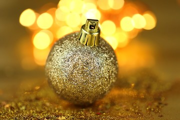 Christmas ball decor. Golden glitter ball on golden blurry bokeh background.Christmas and New Year winter festive background.Phone christmas wallpaper