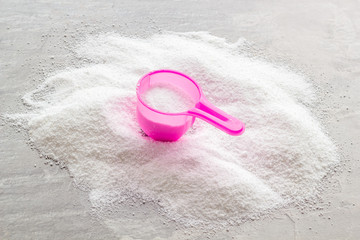 Household chemicals. Washing powder in plastic spoon on grey background