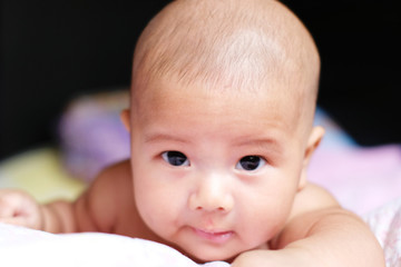 Portrait of a cute 2 months Asian baby on the bed.