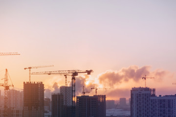 Panorama of construction at sunset. Construction of a residential complex with cranes.