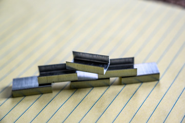 pyrimidine stack of stapler refill clips on lined paper pad