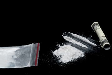 Cocaine or other illegal drugs, white powder, syringe, isolated on black glossy background