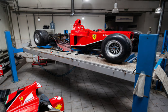 The process of repairing and restoring a red Ferrari Formula 1 car at a pitstop in the service station or a repair workshop on a lift.
