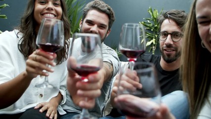Smiling young people clinking glasses with camera. Cheerful friends drinking red wine and waving to camera. Leisure concept - Powered by Adobe