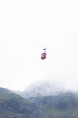 Cable car above green mountainous district on cloudy weather