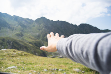 Hand of anonymous tourist in front of green highlands
