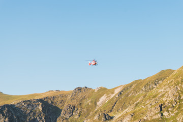 Helicopter among mountainous district in blue sky