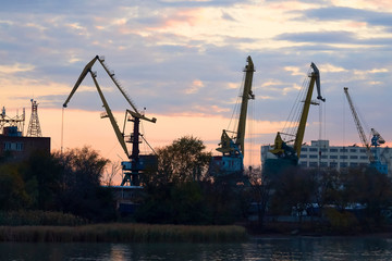 Harbor cranes craned their necks against the beautiful multicolored evening sky . Sunset in the port. Landscape.