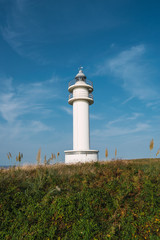 Old lighthouse tower standing on hill in summer