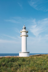 White lighthouse on shoreline in summer